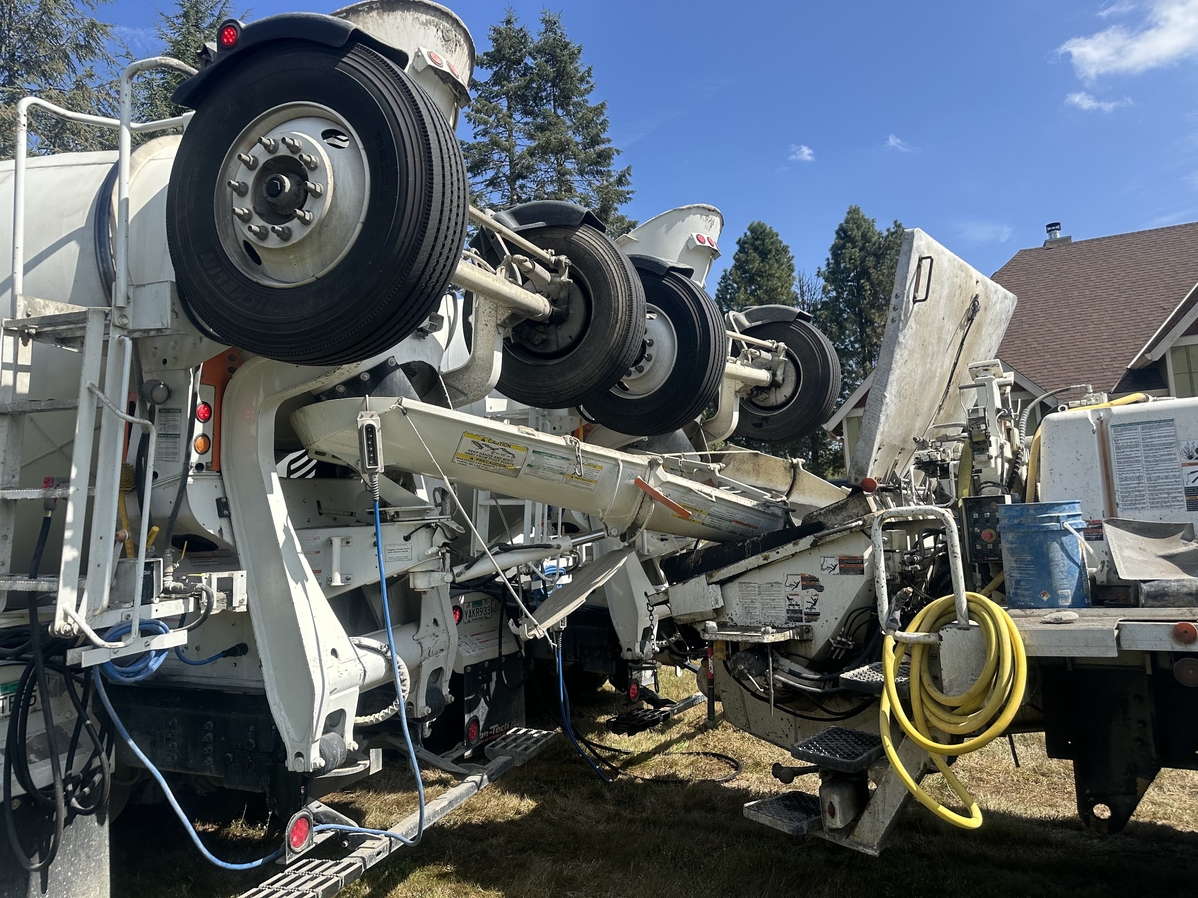 White Con-Tech barrel mixer rear with the chute feeding a pump hopper on a Volume Concrete jobsite